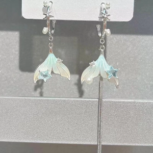 Detail of asymmetric fishtail earrings with mint enamel, pearls, and silver tassels