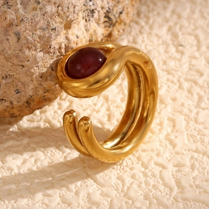 Macro shot of 18K gold double-layered line ring with deep red gemstone on rock