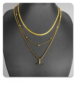 Detailed view of golden triple-layered necklace with snake chain and cross pendant