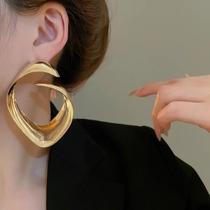 Primo piano di orecchini geometrici a spirale dorati indossati da una modella elegante