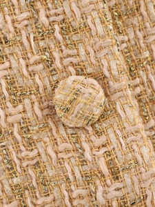Macro shot of champagne tweed fabric texture with gold metallic threads and a matching button