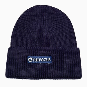 Close-up of navy blue ribbed beanie featuring THE FOCUS woven label and knit texture