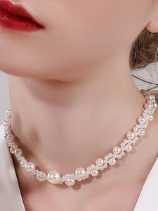 Close-up of elegant white woven pearl choker necklace on model's neckline