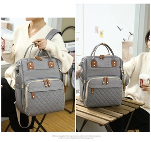 Detail of grey baby bag with quilted front pocket, leather zippers and a side coin pouch