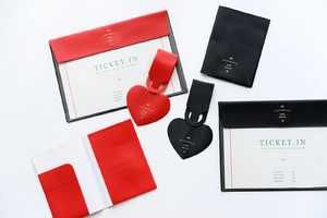 Detail view of red and black faux leather passport holder and heart-shaped luggage tag set