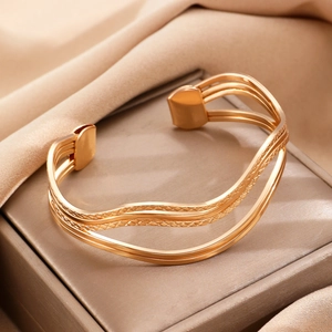 Gedetailleerde opname van een drielaagse golvende gouden armband met fijne gravering