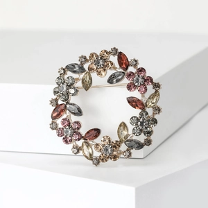 Elegant rhinestone wreath brooch featuring multi-color crystals on a white pedestal