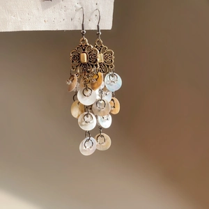 Detailed close-up of bohemian fish shell tassel earrings with vintage bronze hooks