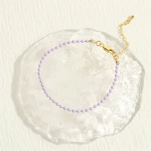 Detail of light purple beaded bracelet with gold lobster clasp on artistic background