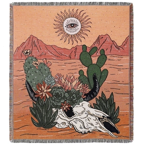 Bohemian woven picnic blanket with desert skull pattern and sun design on white background