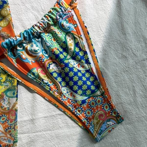Macro detail of paisley print bikini bottom with vibrant orange, green and blue patterns