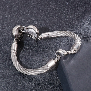 Vue détaillée du bracelet câble en acier argenté avec breloques crâne et fermoir mousqueton