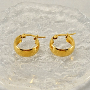 Polished 18k gold stainless steel hoop earrings with latch back closure on glass tray