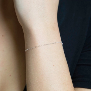 Close-up of minimalist silver slender chain bracelet on wrist showing delicate links