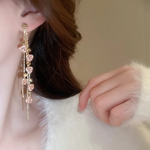 Gros plan de boucles d'oreilles à pompons dorés et roses roses sur le profil d'un modèle