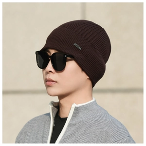 Detailed texture of dark brown ribbed knit beanie with small metallic logo plate