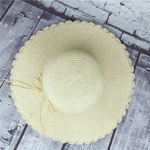 Detail view of beige straw hat featuring delicate lace brim and fine woven texture