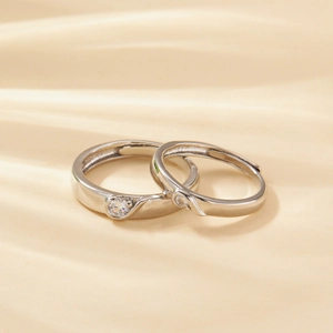 Macro detail of silver couple rings set with cubic zirconia on beige silk background