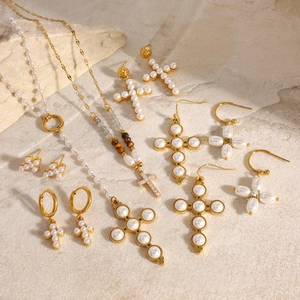 Detailed set of gold cross jewelry with pearls and rhinestones on marble background