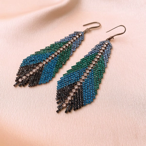 Macro shot of silver feather earrings with gradient blue and green crystal tassels