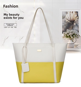Detail of yellow and beige contrast stitching tote bag with gold logo and long shoulder strap