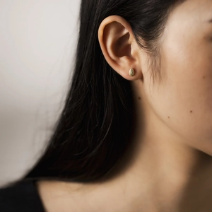 Elegant gold teardrop stud earrings with pavé crystals shown on a female model