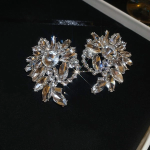Detailed close-up of crystal flower stud earrings on black velvet background with sparkling stones