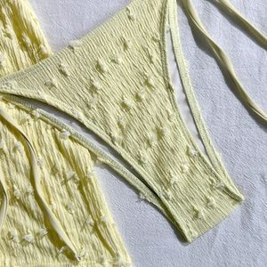 Dettaglio del tessuto bikini giallo chiaro con trama a pieghe e pois svizzeri