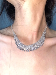 Macro detail of multi-row rhinestone fringe necklace on neck with silver finish