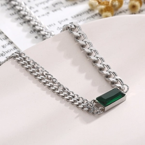 Detailed close-up of a silver double Cuban chain bracelet with a green emerald pendant