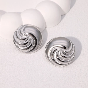 Macro shot of silver circular earrings with 3D spiral texture and polished finish