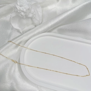 Close-up of fine S925 sterling silver gold-plated satellite chain with beads on silk
