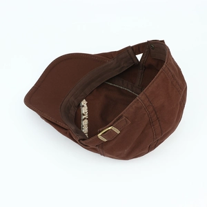 Detail of brown cotton beret featuring inner sweatband, embroidery and bronze metal buckle