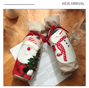 Detail of burlap Christmas wine bottle covers with Santa and snowman embroidery
