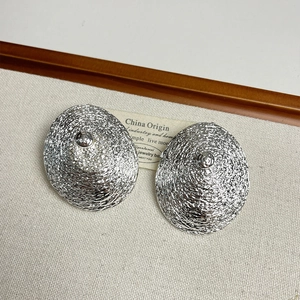 Vue détaillée des boucles d'oreilles coniques argentées avec texture métal martelée