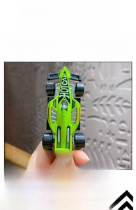 Close-up of a neon green mini racing car keychain with sleek aerodynamic F1 design