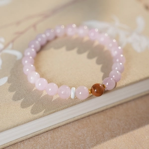 Detailed close-up of beaded bracelet with pink crystals and golden metal accents