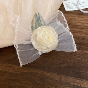 Détail macro du bracelet rose en dentelle blanche avec nœud en organza sur bois