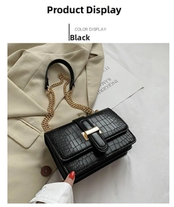 Detail of black crocodile pattern leather bag with golden metallic clasp and chain strap