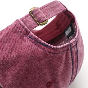 Macro detail of wine red washed canvas baseball cap with adjustable bronze buckle and strap