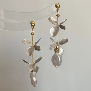 Detail view of butterfly tassel earrings with baroque pearls and floral silver petals