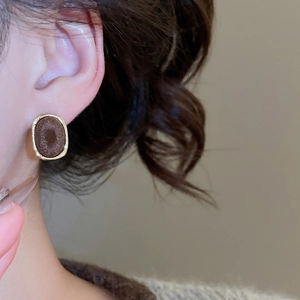 Detail of vintage heart earrings with brown flocking and textured gold border