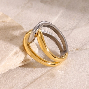 Macro view of interlocking gold and silver stainless steel rings on a natural stone surface