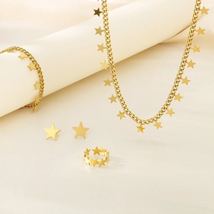 Gold star jewelry set with tassel necklace, bracelet, earrings and ring on a prop