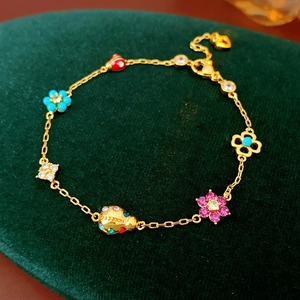 Close-up of gold chain bracelet with colorful flower and ladybug enamel charms