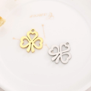 Minimalist clover heart pendants in gold and silver steel finish on a ceramic plate
