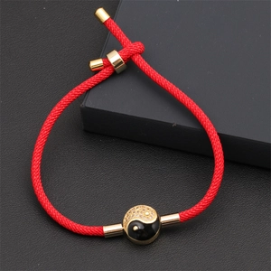 Detailed view of red braided Milan cord bracelet with gold yin yang charm on display