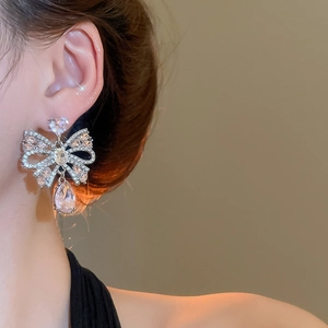 Close-up of sparkling bow earrings with water drop crystal on a female model