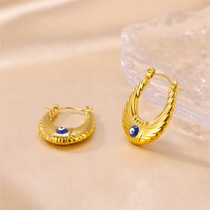 Golden U-shaped earrings with blue evil eye design on elegant champagne silk