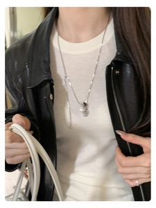 Detailed shot of silver tiger eye pearl pendant necklace on a leather jacket outfit
